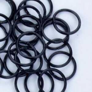 May include: A pile of black metal key rings. The rings are all the same size and are arranged in a random pattern.
