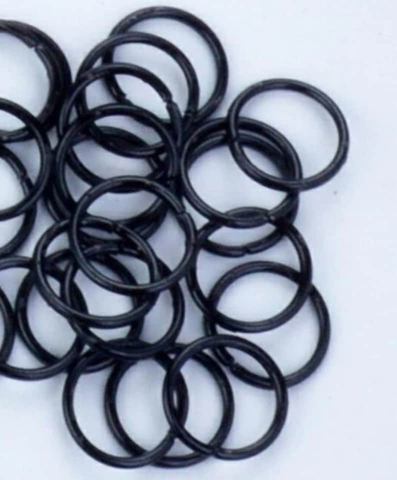 May include: A pile of black metal key rings. The rings are all the same size and are arranged in a random pattern.