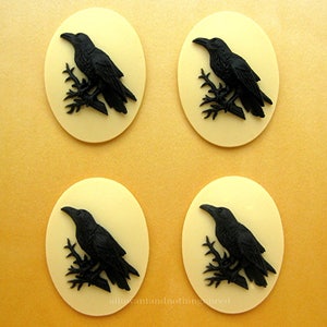 May include: Four black cameo-style buttons with a raven perched on a branch. The buttons are oval shaped and have a cream background.