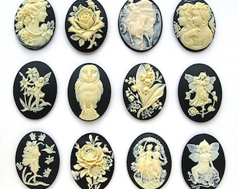 May include: Twelve black cameo pendants with white raised designs. The designs include a rose, a fairy, a bird, a woman, a flower, and a group of fairies.