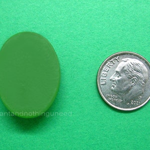 May include: A green oval-shaped glass piece, approximately the size of a dime.