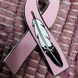 May include: A pink ribbon with a black and white feather design. The ribbon is a symbol of support for breast cancer awareness.