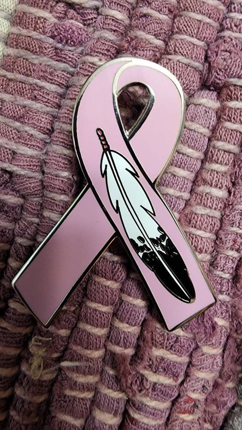 May include: A pink ribbon with a black and white feather design. The ribbon is a symbol of support for breast cancer awareness.