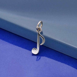 Peut inclure: Un pendentif en argent en forme de note de musique. Le charme est en forme de clé de sol et a une boucle en haut pour l'attacher à un collier ou un bracelet.