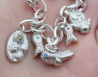 Pulsera con dije marino que incluye una foca, una tortuga marina, peces y una poza de marea en plata. Esta pulsera oceánica es el regalo perfecto para un buceador o un pisciano.