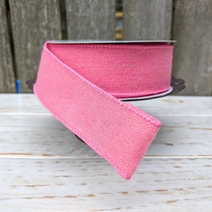 Op de afbeelding: Een rol roze jute lint met een bedrade rand. Het lint is 2,5 inch breed en heeft een zachte, textuur.