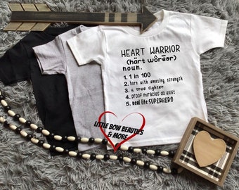 May include: White t-shirt with black text that reads "HEART WARRIOR (härt wôrear) noun. 1. 1 in 100 2. born with amazing strength 3. a true fighter 4. proof miracles do exist 5. Real life SUPERHERO".