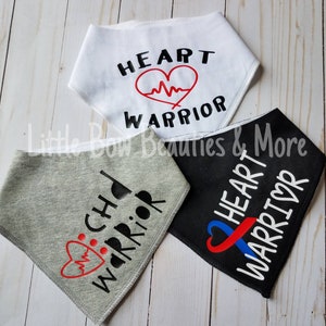 May include: Three dog bandanas with different designs. One is white with black text that says "HEART WARRIOR" and a red heart with a heartbeat line. One is gray with black text that says "CHD WARRIOR" and a red heart with a heartbeat line. One is black with white text that says "HEART WARRIOR" and a blue and red ribbon with a heart in the center.