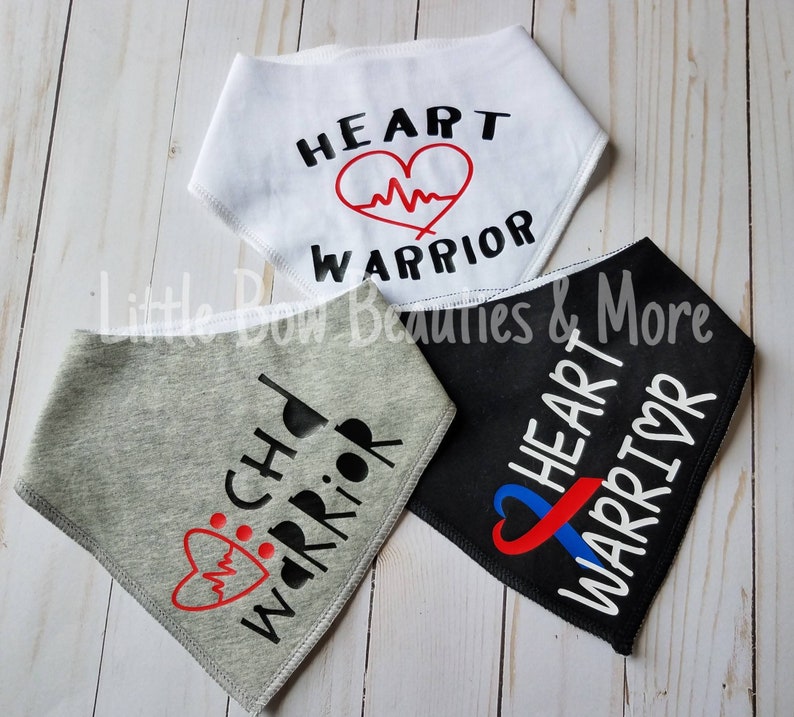 May include: Three dog bandanas with different designs. One is white with black text that says "HEART WARRIOR" and a red heart with a heartbeat line. One is gray with black text that says "CHD WARRIOR" and a red heart with a heartbeat line. One is black with white text that says "HEART WARRIOR" and a blue and red ribbon with a heart in the center.