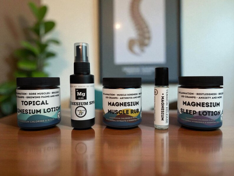 Puede incluir: Una colecci&oacute;n de productos de magnesio, incluyendo lociones, sprays y un roll-on, con tapas negras y etiquetas blancas. Las etiquetas presentan textos como "Topical Magnesium Lotion" y "Magnesium Sleep Lotion". Los productos est&aacute;n sobre una superficie de madera.