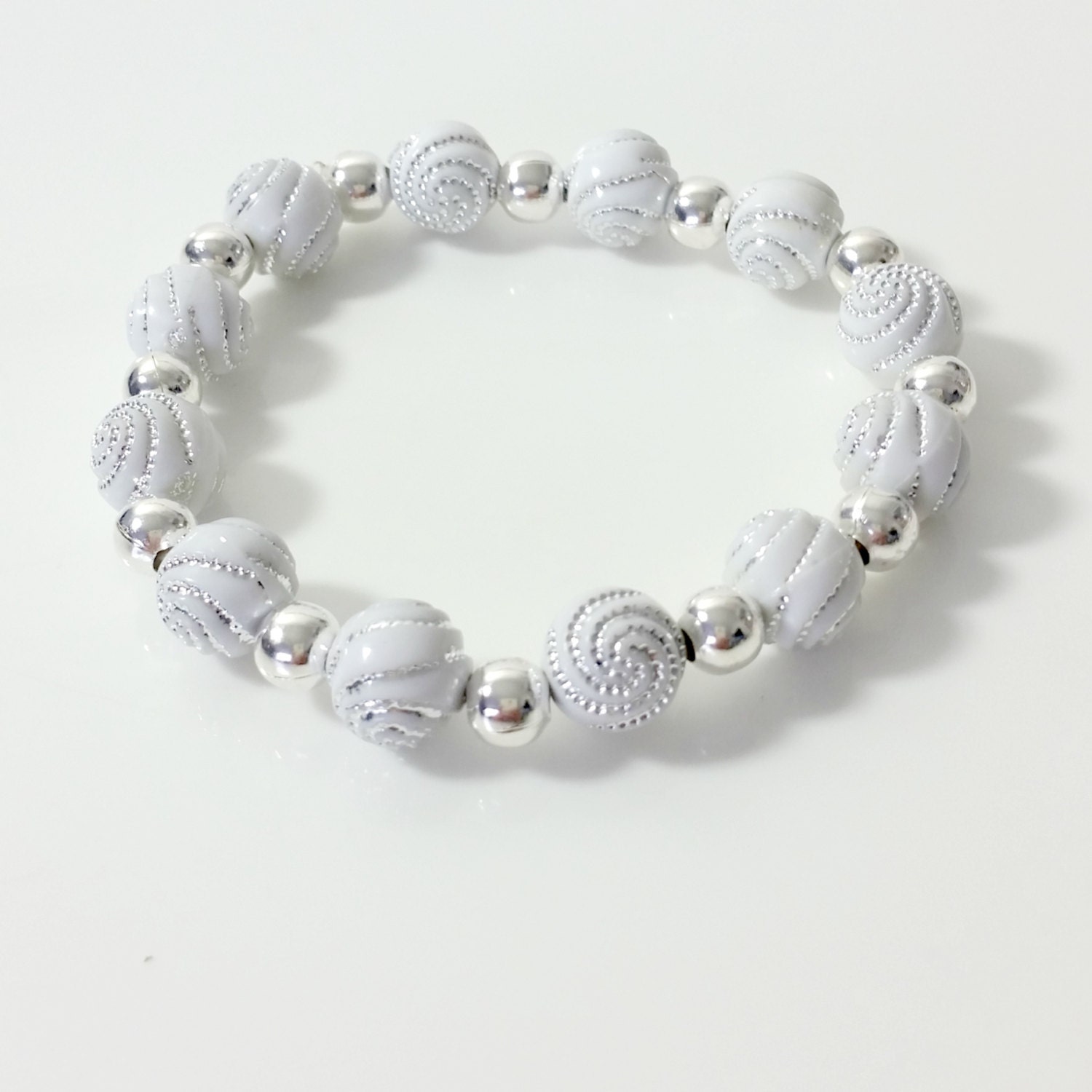 Pulsera elástca con cuentas de resna y abaloros. Tonos metalzados
