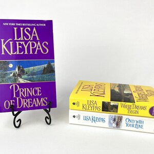 May include: A stack of three books by Lisa Kleypas. The book on the left is titled "Prince of Dreams" with a purple cover. Two other books are stacked to the right, one yellow and one white, with the titles "Where Dreams Begin" and "Only With Your Love".