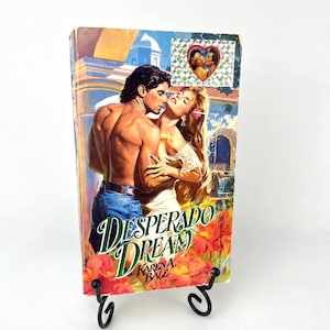 May include: A paperback romance novel titled "Desperado Dream" by Karey A. Bale. The cover features a couple embracing in a romantic setting with a colorful background.