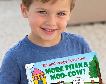 May include: A children's book titled More Than a Moo-Cow! by Sally Helmick North. The cover features a cartoon illustration of a brown cow, a yellow house with a pink roof, a green tree, and a speech bubble with the text mooo mooo mooo!