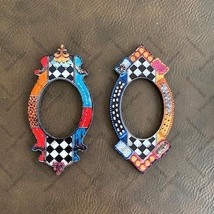 May include: Two colorful wooden frames with a checkered pattern, red, blue, orange, and black accents. The frames are shaped like a crown with a rounded opening in the center.