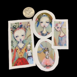 May include: Four oval-shaped fabric patches with watercolor paintings of girls with flowers in their hair. The girls are wearing colorful dresses and have light skin and blue eyes. The patches are on a dark background.