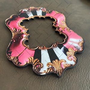 May include: A decorative, ornate frame with a pink and black striped center. The frame has gold-colored filigree accents and a black border. The word "Wunderland" is repeated across the image.