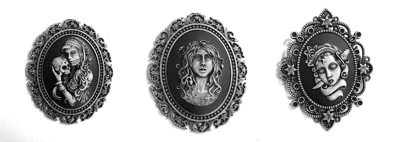 May include: Three silver-toned cameo brooches with ornate frames. Each brooch features a black and white portrait of a woman with a different expression.