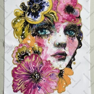May include: Watercolor painting of a woman's face adorned with flowers. The artwork features a woman with blue eyes, pink lips, and a floral arrangement of pink, purple, yellow, and orange blooms. The background is white.