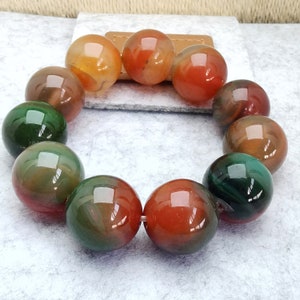 May include: A bracelet made of round, multi-coloured agate beads. The beads are a mix of green, orange, and red.