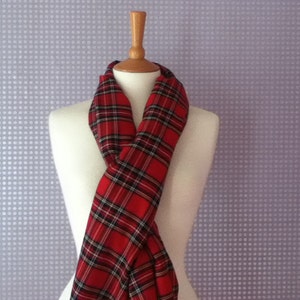 May include: Red and black tartan scarf with a white background. The scarf is folded and draped over a mannequin.