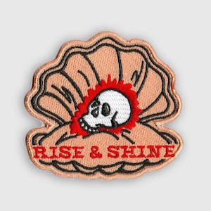 May include: An embroidered patch in pink with a skull inside a seashell and the text "RISE & SHINE" in red.