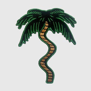 May include: Embroidered patch depicting a palm tree. The palm fronds are dark green with a lighter green outline, and the trunk is a light brown with a textured appearance. The patch has a black background and a green border.