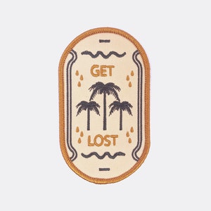 May include: A beige embroidered patch with a brown border. The patch features a palm tree design with the text "GET LOST" in orange.