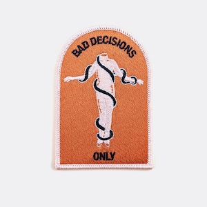 May include: An orange embroidered patch with a white outline. The patch features a white figure with a snake wrapped around it. The text "BAD DECISIONS ONLY" is embroidered in black.