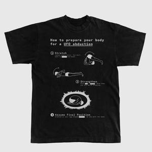 Könnte beinhalten: Schwarzes T-Shirt mit weißem Text und Illustrationen, die erklären, wie man sich auf eine UFO-Entführung vorbereitet. Das Shirt enthält Anweisungen zum Dehnen, Kräftigen und Einnehmen einer Endposition mit Diagrammen.