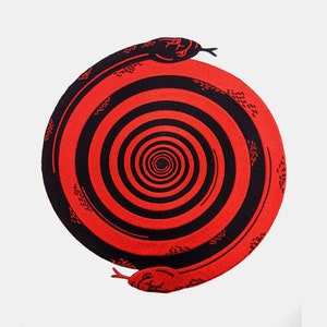 May include: A black and red circular rug with a spiral pattern in the centre. The rug is shaped like a snake with its tail in its mouth.