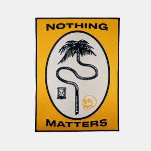 Könnte beinhalten: Gelber und schwarzer gestickter Patch mit dem Text "NOTHING MATTERS" und einer Palme mit einem Totenkopf und einer Sanduhr in einem Oval.