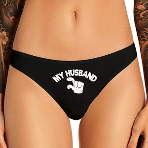 Puede incluir: Ropa interior de encaje negro con el texto "Mi marido" y una mano de dibujos animados haciendo un pulgar hacia arriba.