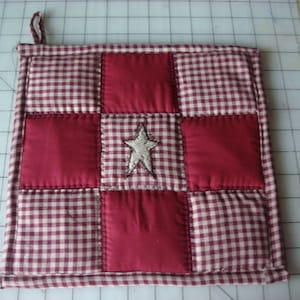 May include: Red and white gingham patchwork hot pad with a white embroidered star in the center.