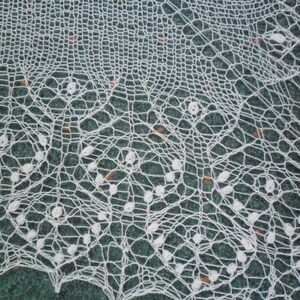 May include: White crocheted lace doily with a delicate floral pattern. The lace is intricate and has a fine texture.