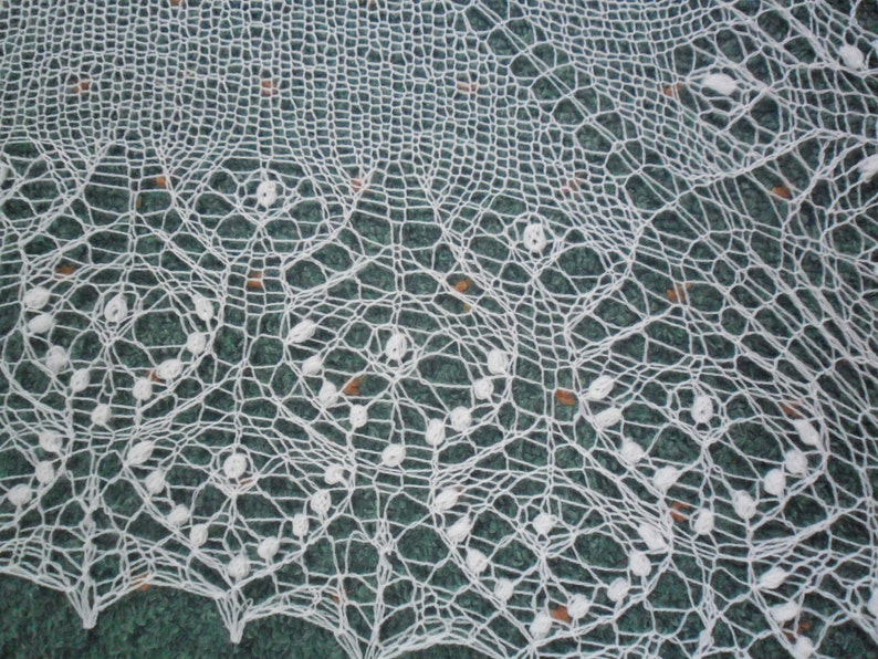 May include: White crocheted lace doily with a delicate floral pattern. The lace is intricate and has a fine texture.