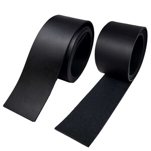 May include: Two rolls of black leather strips are displayed against a white background. One roll is partially unrolled, revealing the smooth, shiny surface of the leather. The other roll is tightly wound, showing the edge of the leather. The leather appears to be of high quality.
