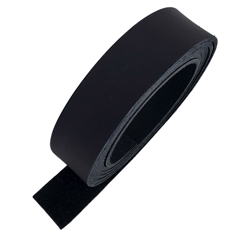 May include: A roll of black leather strip, tightly coiled. The leather has a smooth, shiny surface on one side and a textured, suede-like finish on the other. The strip is unrolled at the end, revealing the suede side.