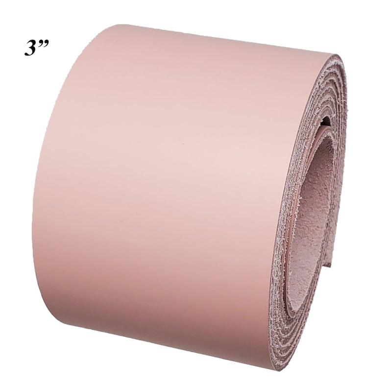 Op de afbeelding: Een rol blush roze leer, ongeveer 7,6 cm breed, wordt getoond tegen een witte achtergrond. Het leer is strak opgerold, waardoor de randen van het materiaal zichtbaar zijn. De tekst "3" is zichtbaar in de linkerbovenhoek.