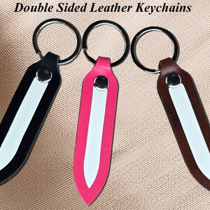 May include: Three double-sided leather keychains in black, pink, and brown. Each keychain has a silver ring and a white stripe down the center. The text "Double Sided Leather Keychains" is at the top.