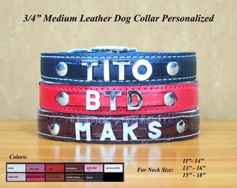 Op de afbeelding: Drie gepersonaliseerde leren hondenhalsbanden gestapeld, elk met een andere naam in zilveren letters. De bovenste halsband is marineblauw, de middelste rood en de onderste bruin. De halsbanden zijn 1,9 cm breed.