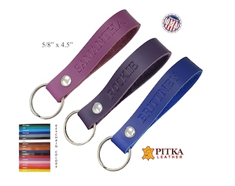 May include: Three leather keychains in purple, dark purple, and blue, each with a name embossed on the strap. The keychains are 5/8" x 4.5" and have a silver metal ring. The image also shows a color chart and the "Made in the USA" logo.
