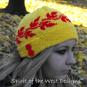 May include: A yellow knitted hat with red and yellow leaf designs. The hat has a pompom on top and is made of a soft, warm yarn.