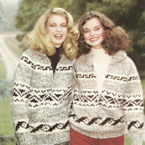 May include: Two women wearing grey and white patterned sweaters with brown accents. The sweaters have a zip closure and a geometric design. The women are standing in front of a blurred background of trees. The text "PAT. 1" is visible at the bottom of the image.