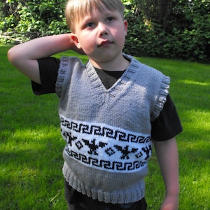 Peut inclure: Un jeune portant un gilet en tricot gris avec un motif géométrique blanc et noir. Le gilet a un col en V et est porté sur une chemise noire.