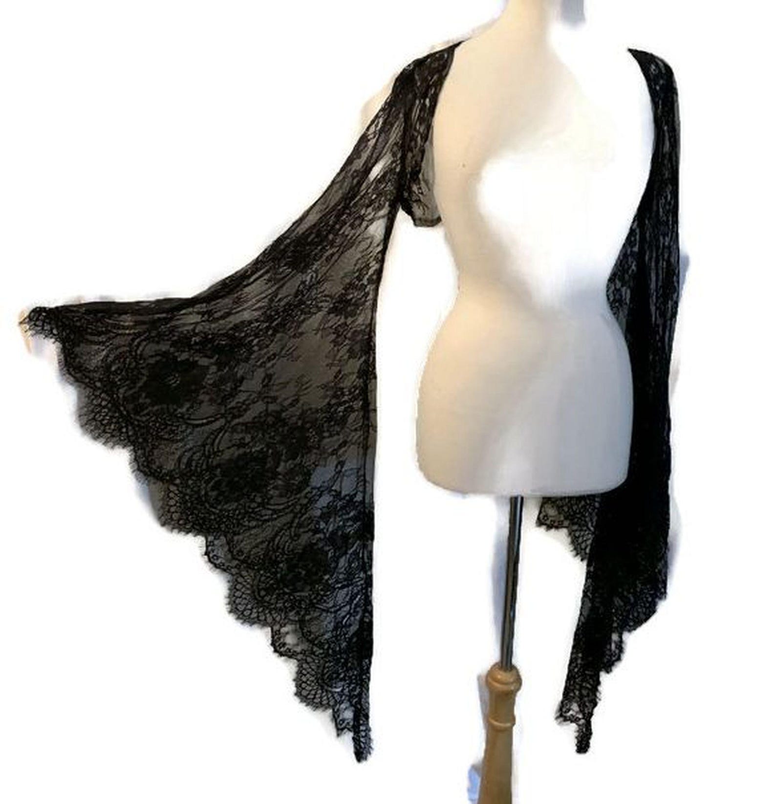 Black lace triangle shawl with a gothic floral pattern, displayed on a dress form with dramatic scalloped edges and draped sleeves.