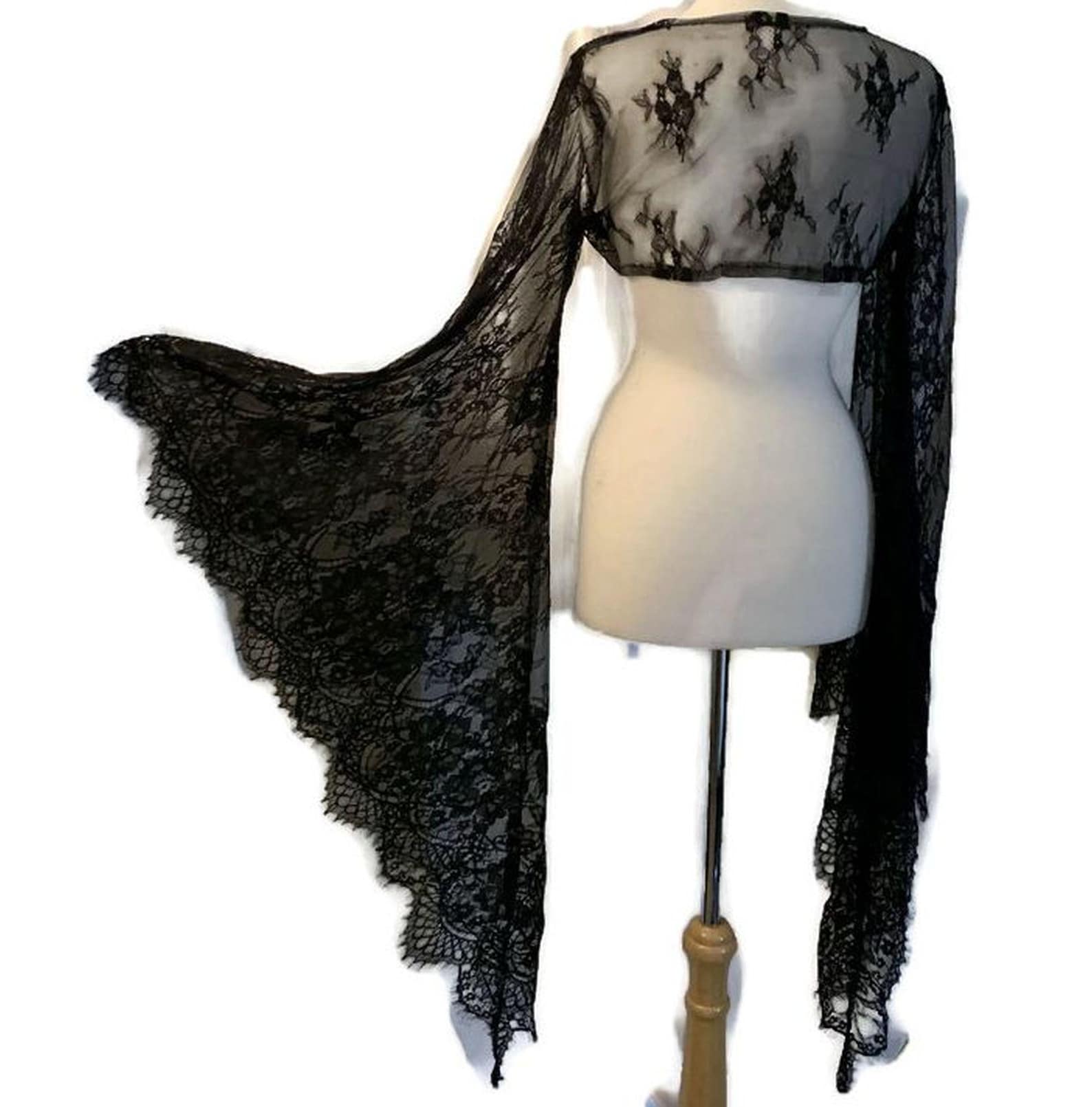 Back view of a gothic black lace shawl with bell sleeves and floral web motifs, styled in a triangle cut with trailing edges.