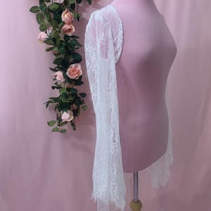 Side profile of the romantic lace jacket showing the 25 inch long sleeve length from the shoulder down to the fringed hem.