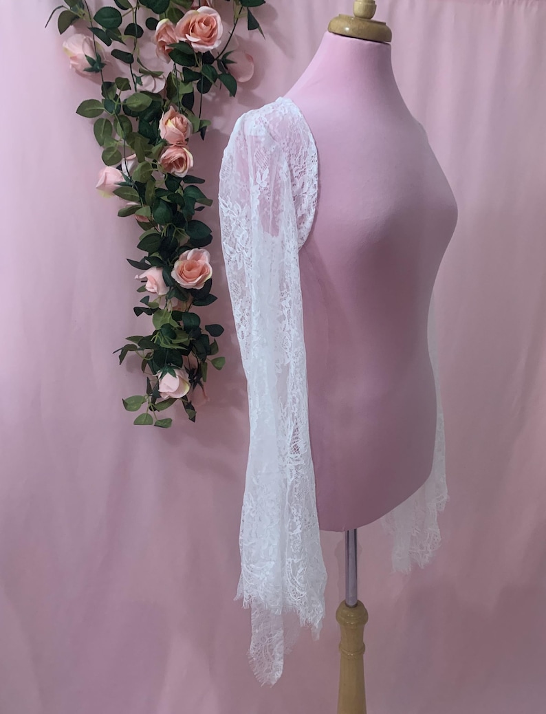 Side profile of the romantic lace jacket showing the 25 inch long sleeve length from the shoulder down to the fringed hem.