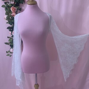Close-up shot of the white lace fabric highlighting the delicate eyelash fringe details and intricate floral pattern.